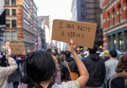 Stop Asian Hate march, back of woman's head who is holding a sign that says "I am not a virus"